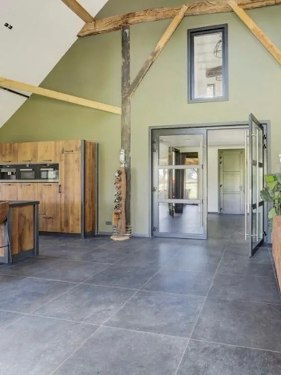 Woonkeuken met een olijfgroen getexte wand tussen houten spanten
